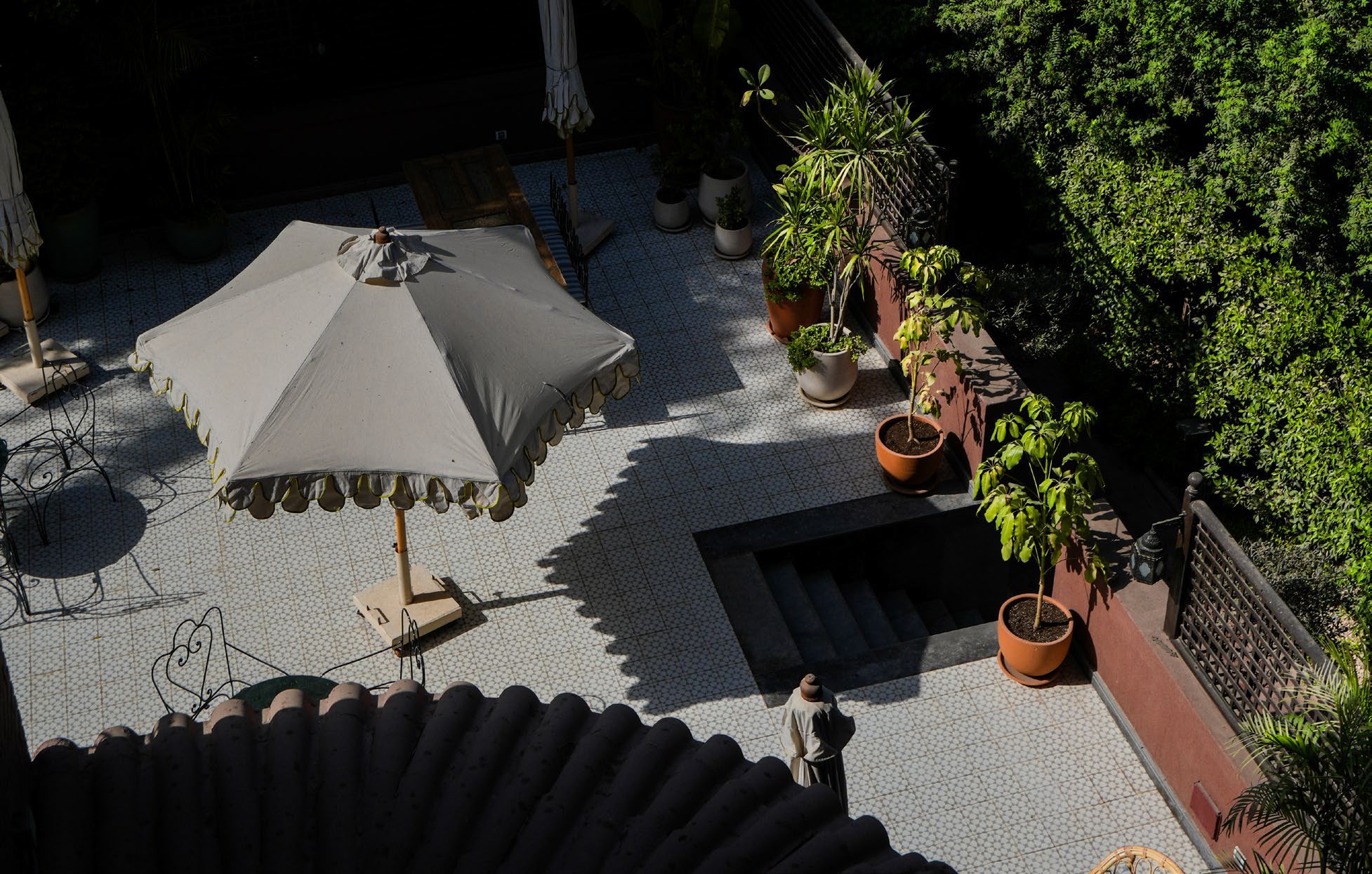 The courtyard at Villa Atouta from above — parasols, patterned tile and deep green trees